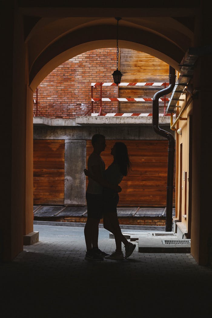 Silhouette of a couple embracing under an archway at sunset in Minsk.